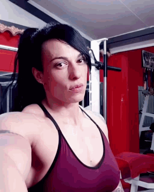 a woman in a purple tank top is standing in a gym with a sign that says power