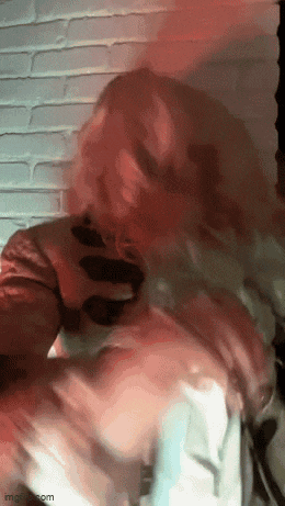 a close up of a person 's face with a brick wall in the background
