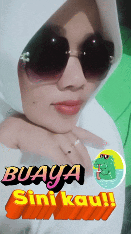 a woman wearing sunglasses and a hijab with buaya sini kau written on the bottom