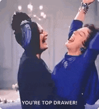 two women are standing next to each other and laughing .