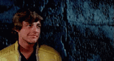 a man in a yellow jacket is smiling while standing in front of a blue wall .