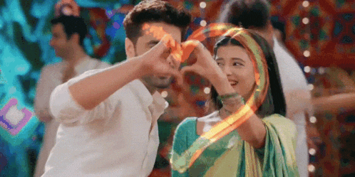 a man and a woman are making a heart shape with their hands while dancing .