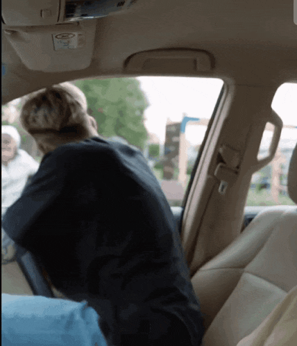 a person sitting in a car with a sticker on the ceiling that says ' airbag '
