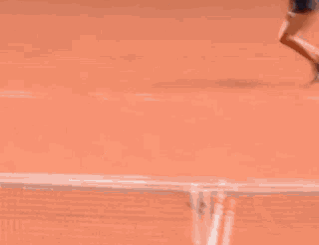 a tennis player is hitting a tennis ball on a clay court .