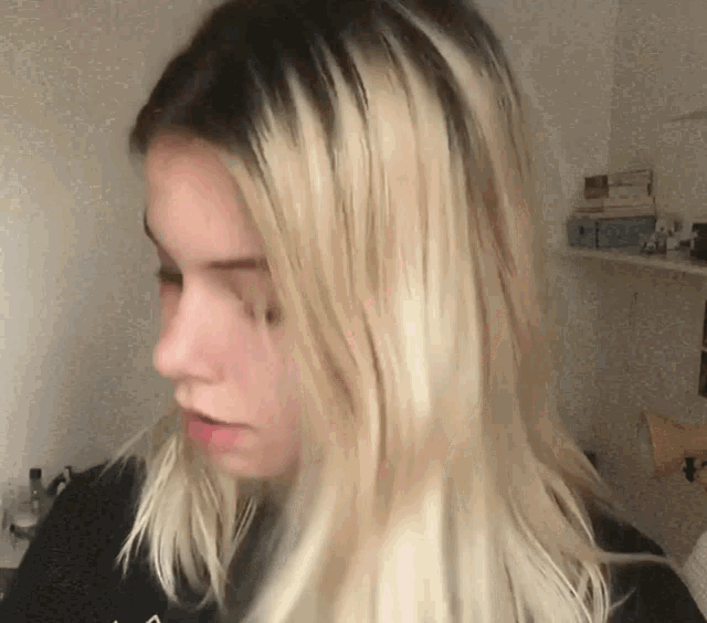 a woman with blonde hair is wearing a black shirt with the letter a on the front