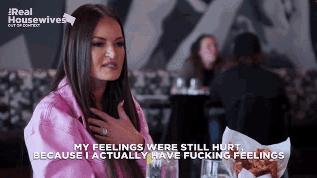 a woman is sitting at a table with her hand on her chest and the words " my feelings were still hurt "