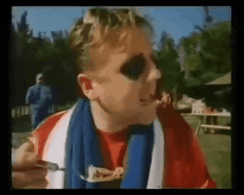 a man wearing sunglasses and a scarf is eating noodles .