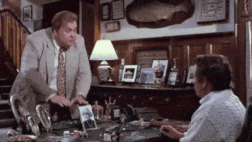 a man in a suit and tie is standing next to another man in a living room .