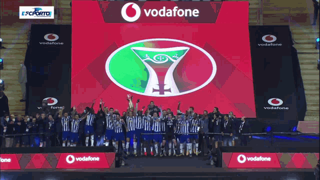 a group of soccer players are standing in front of a large screen that says vodafone
