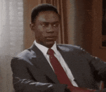 a man in a suit and tie is sitting in a chair looking at the camera .