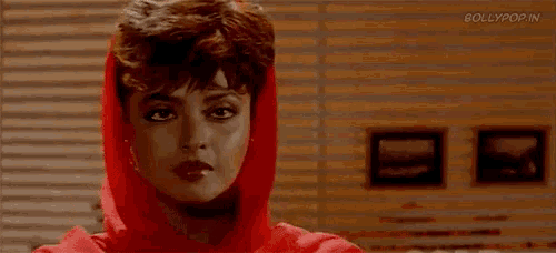 a woman wearing sunglasses and a red hat is holding her hands to her ears .