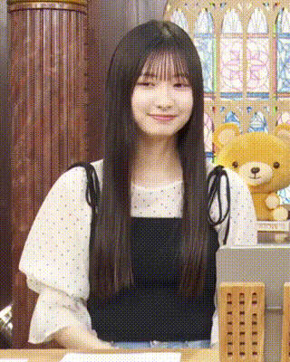 a girl with long hair is standing in front of a teddy bear .