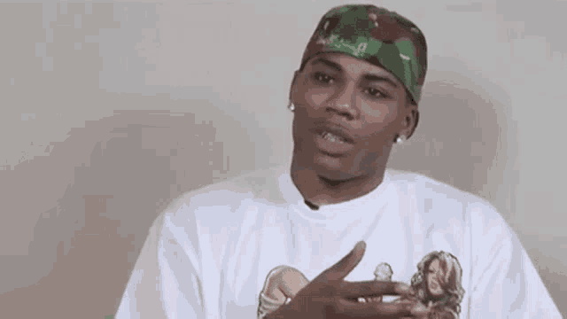 a man wearing a white t-shirt and a camouflage hat is talking .