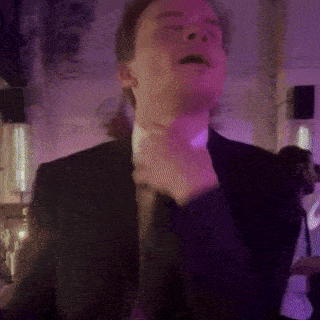a man in a suit and tie is dancing with his eyes closed .