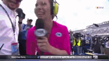 a woman in a pink shirt is talking into a microphone while wearing headphones .
