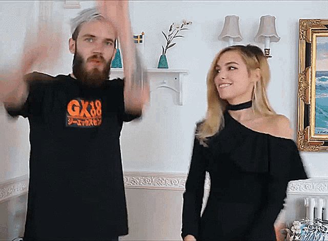 a man wearing a shirt that says gk38 stands next to a woman in a black dress
