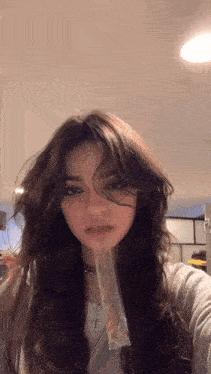 a girl with long hair is taking a selfie with a plastic bag between her teeth .