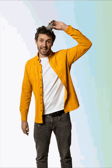 a man in a yellow shirt is holding a small green object