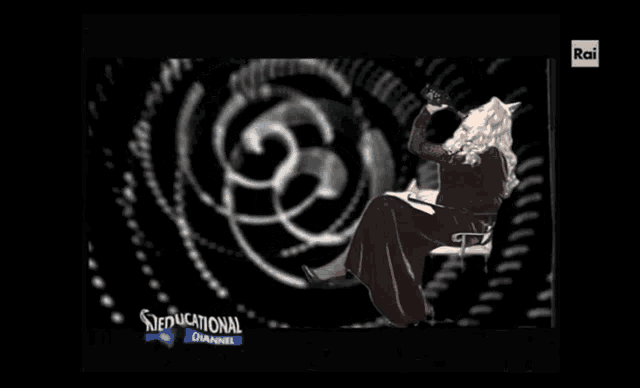 a woman sits on a chair in front of a screen that says rai