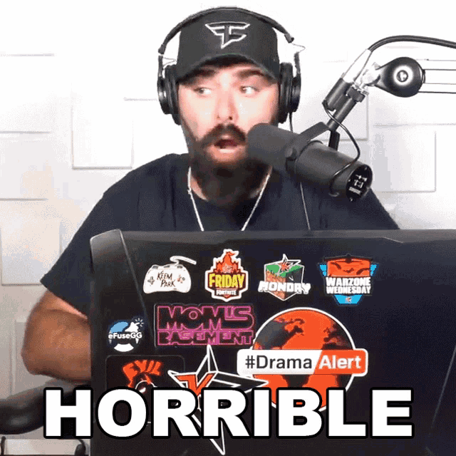 a man wearing headphones sitting in front of a microphone with the word horrible written on the screen