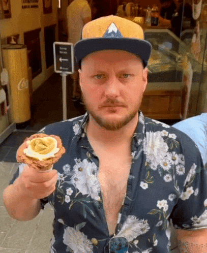 a man wearing a hat and a floral shirt is holding a cone