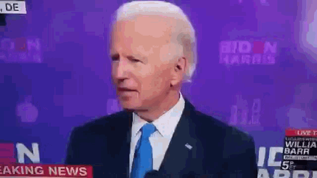 a man in a suit and tie is standing in front of a purple background that says ' breaking news ' on it