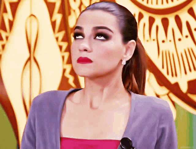 a woman wearing a pink top and a gray cardigan is looking up