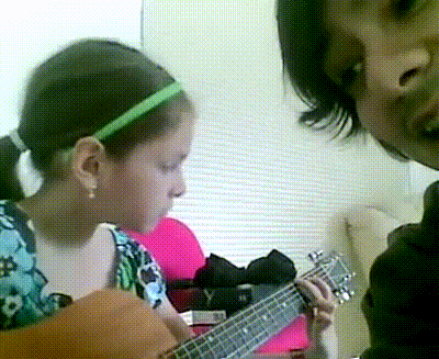 a young girl with a green headband is playing a guitar