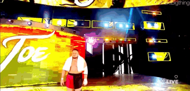a wrestler is walking in front of a wall that says joe on it