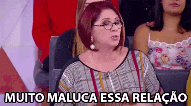a woman with red hair and glasses is sitting in a crowd with the words muito maluca essa relacao below her