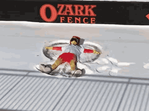 a person is making a snow angel in front of a sign that says ozark fence