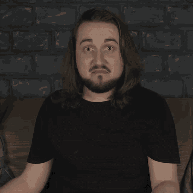 a man with long hair and a beard is sitting on a couch