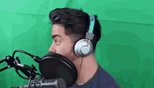 a man wearing headphones is sitting in front of a microphone .