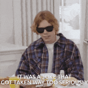 a man wearing sunglasses says it was a joke that got taken way too seriously while sitting at a table