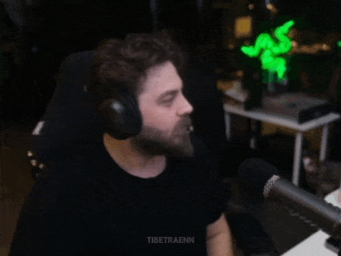 a man with a beard wearing headphones is giving a high five in front of a microphone .