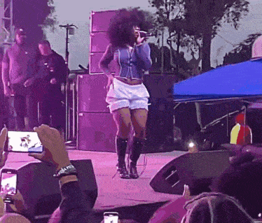a woman singing into a microphone while a crowd watches