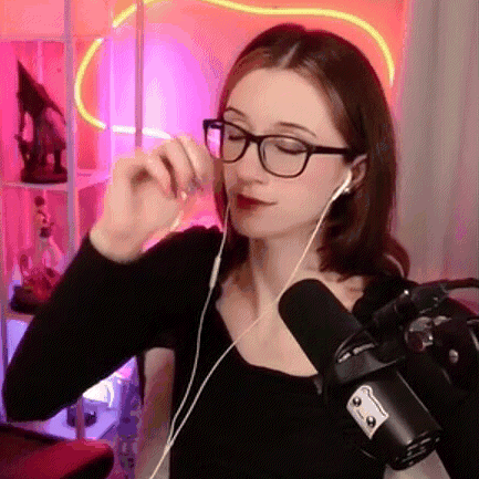 a woman wearing glasses and ear buds is standing in front of a microphone .