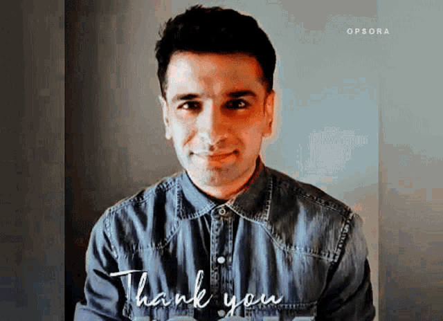 a man in a denim shirt is standing in front of a sign that says " thank you "