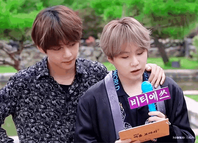 two young men are standing next to each other and one of them is holding a microphone with a sign that says world on it