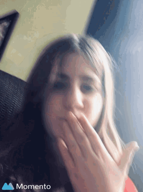 a girl is covering her mouth with her hands and the word momento is on the bottom right