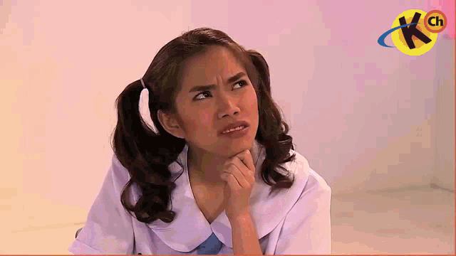 a girl with pigtails is making a funny face in front of a sign that says kch