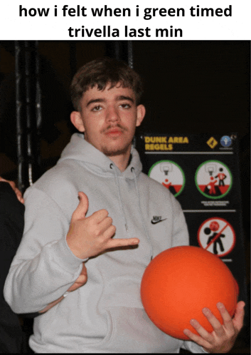 a young man holding an orange ball in front of a dunk area sign