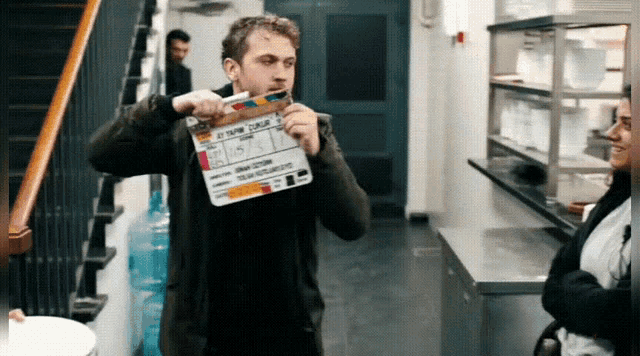 a man is holding a clapper board that says " my name is "