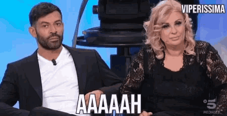 a man and a woman are sitting next to each other and the woman is saying aaaah