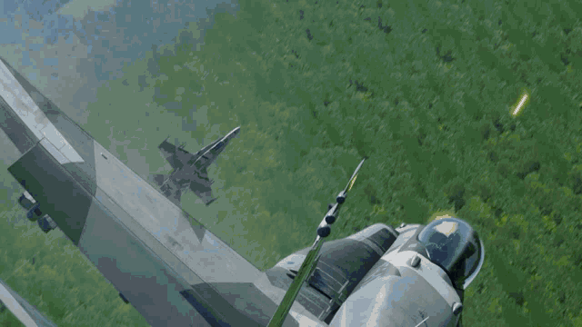 two fighter jets are flying over a grassy field with trees