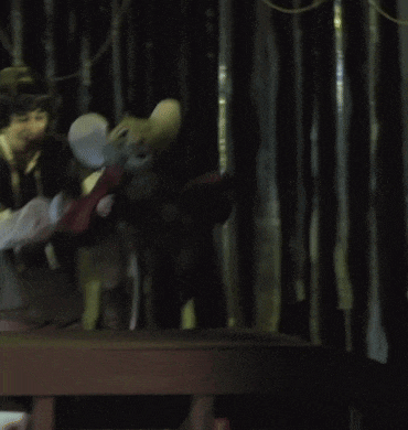 a man in a costume holds a stuffed mouse in his arms