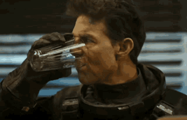 a man in a military uniform is drinking a glass of water from a bottle
