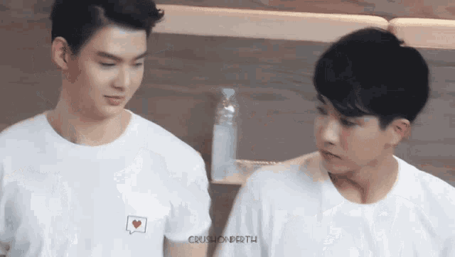 two young men wearing white shirts are standing next to each other .