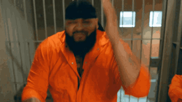 a group of men in orange jumpsuits are laughing in a prison cell