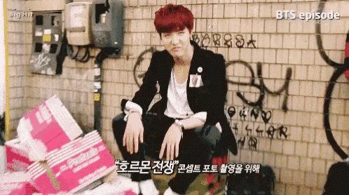 a young man with red hair is sitting in front of a brick wall .